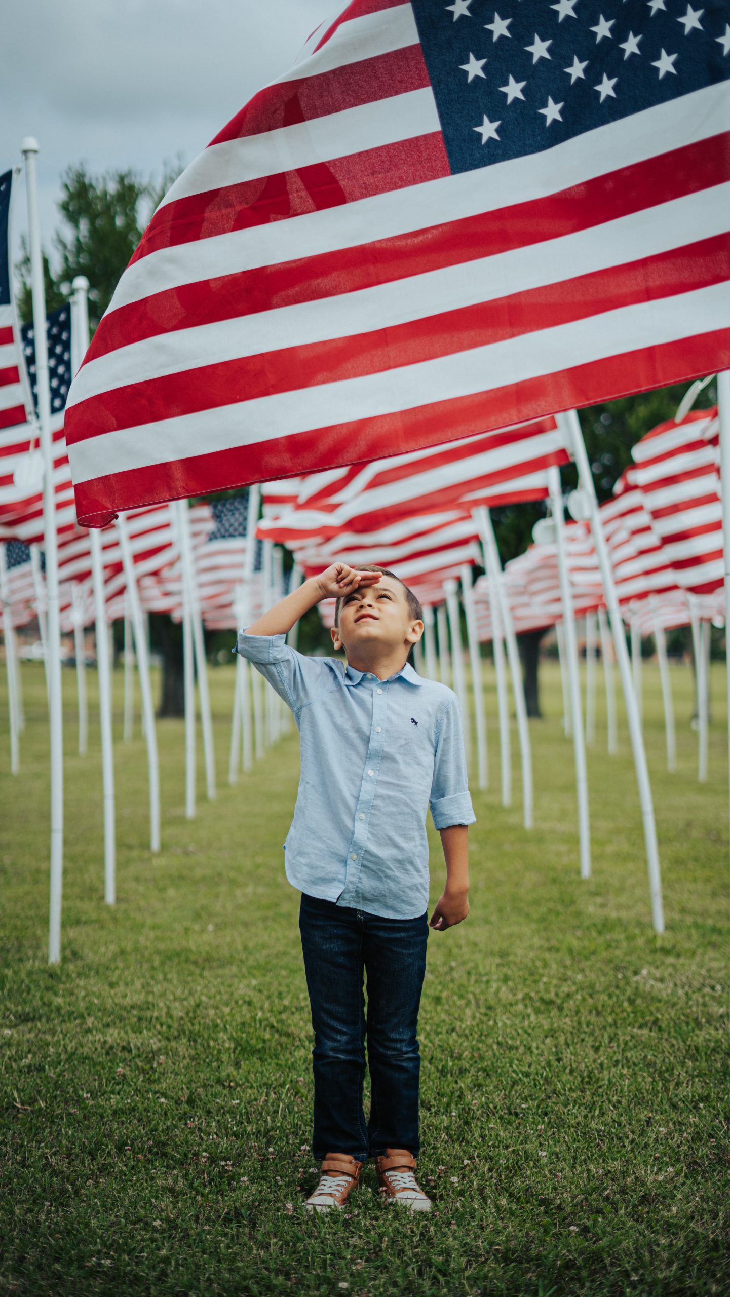 boy in blue dress shirt standing on green grass field during daytime