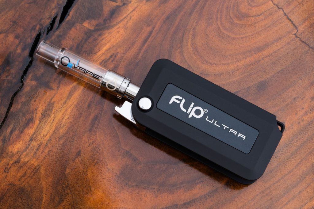 O2VAPE FLIP® ULTRA Vape Pen in a sleek, rectangular design with a matte black finish and branding ‘FLIP® ULTRA’ visible on the body. The device is open, showcasing its unique flip mechanism that conceals the cartridge.