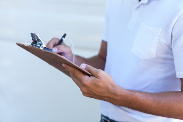 man writing in clipboard