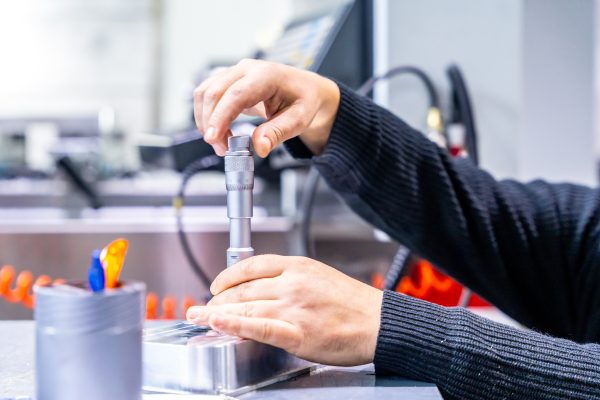 Close-up of an unrecognizable manual worker using tool to fix a metal piece in a cnc modern factory