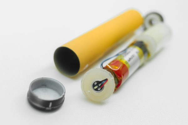 Disassembled into separate parts disposable electronic cigarette. The internal device of the electronic vape for smoking. Repair and disassembly of electronic cigarettes. Selective focus.